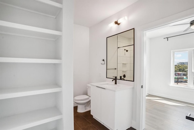 bathroom with walk in shower, vanity, ceiling fan, wood-type flooring, and toilet