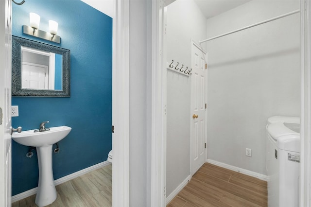 bathroom featuring hardwood / wood-style floors, washer and clothes dryer, and toilet