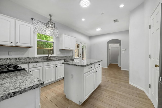 kitchen featuring sink, decorative light fixtures, a center island, light hardwood / wood-style flooring, and white cabinets