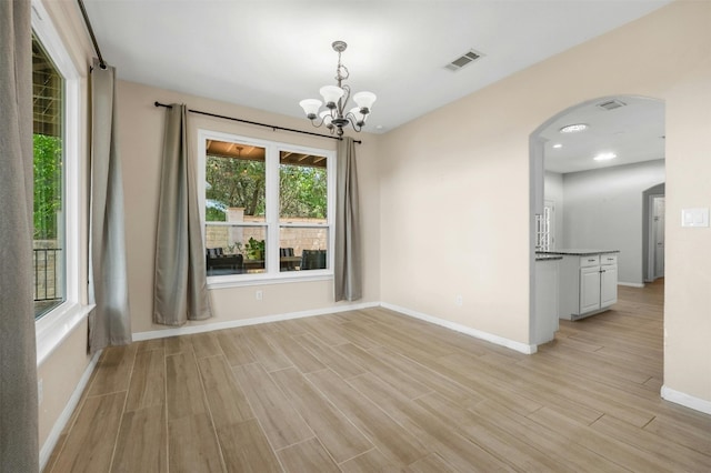 unfurnished dining area with a chandelier and light hardwood / wood-style flooring