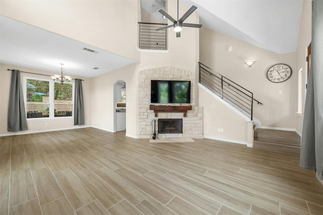 unfurnished living room featuring a towering ceiling, a fireplace, and ceiling fan with notable chandelier