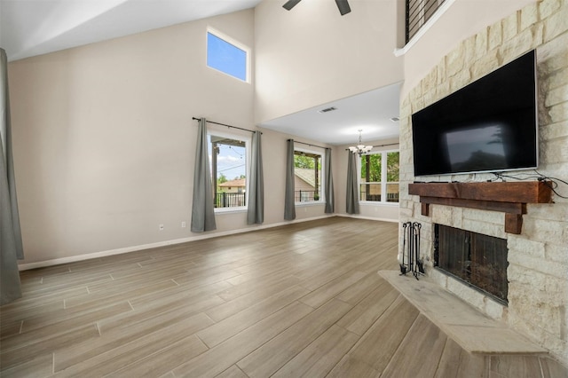 living room featuring a healthy amount of sunlight, a stone fireplace, and light wood-type flooring