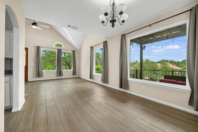 unfurnished living room with ceiling fan with notable chandelier, vaulted ceiling, and light wood-type flooring