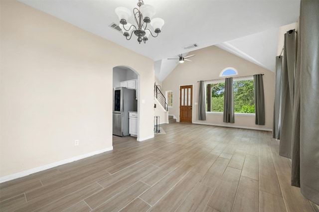 unfurnished living room featuring ceiling fan with notable chandelier, light hardwood / wood-style flooring, and vaulted ceiling