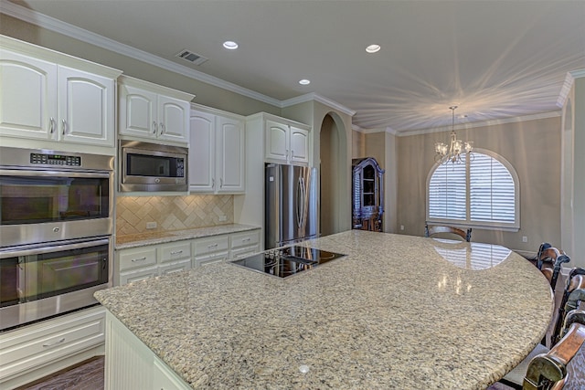 kitchen featuring white cabinetry, light stone counters, backsplash, a chandelier, and appliances with stainless steel finishes