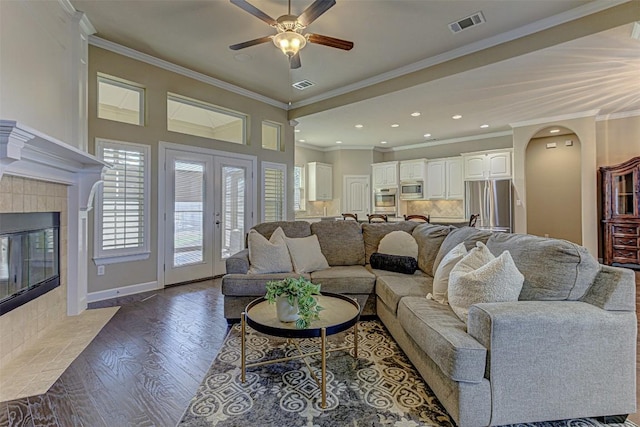 living room featuring a tile fireplace, hardwood / wood-style flooring, ceiling fan, and ornamental molding