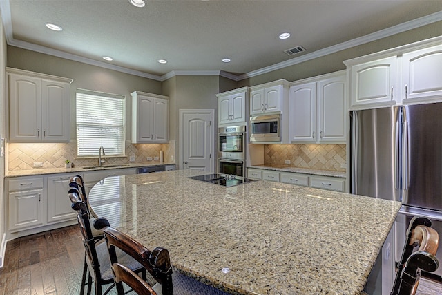 kitchen with white cabinets, a kitchen island, a breakfast bar area, and appliances with stainless steel finishes