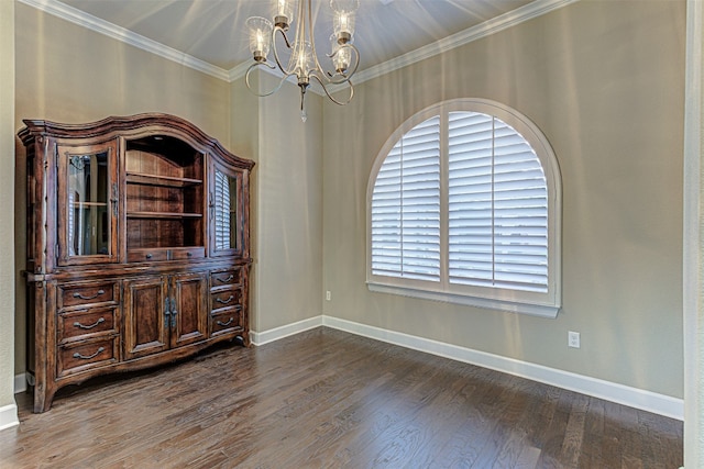 spare room featuring a chandelier, dark hardwood / wood-style floors, and ornamental molding