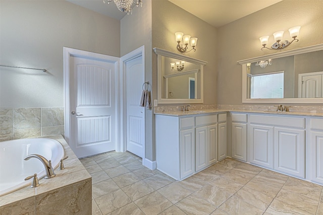 bathroom with tiled tub, vanity, and a notable chandelier