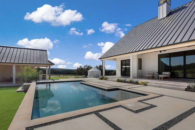 view of swimming pool with a shed and a patio area