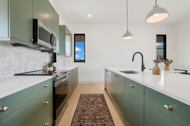 kitchen featuring stainless steel appliances, tasteful backsplash, sink, light hardwood / wood-style floors, and pendant lighting