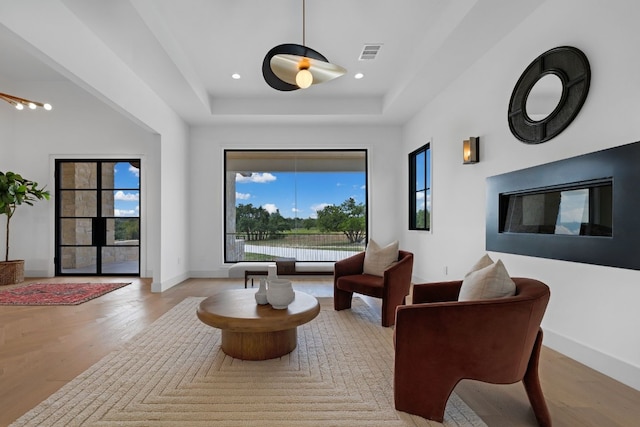 sitting room with light hardwood / wood-style flooring and a tray ceiling