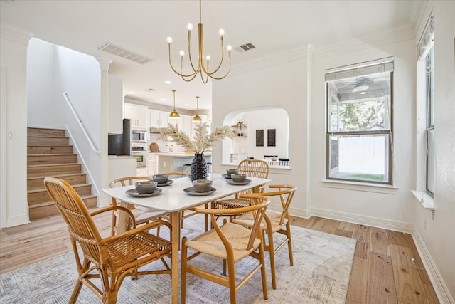 dining area with light hardwood / wood-style flooring, ornamental molding, and a chandelier