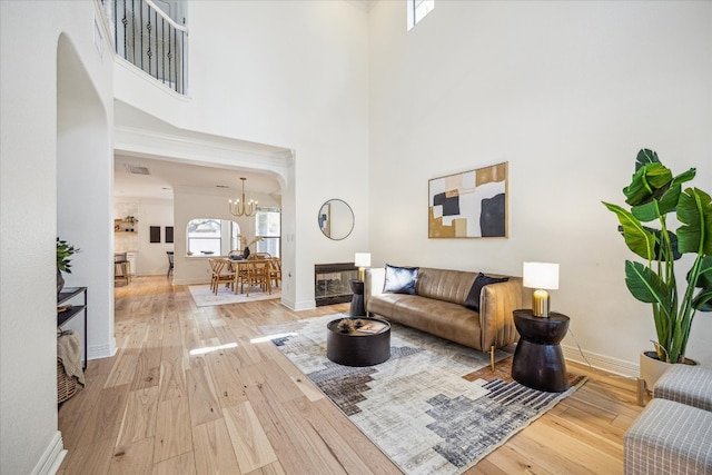 living room with light hardwood / wood-style floors, a high ceiling, and an inviting chandelier