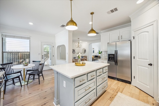 kitchen with crown molding, light hardwood / wood-style flooring, decorative light fixtures, and stainless steel fridge