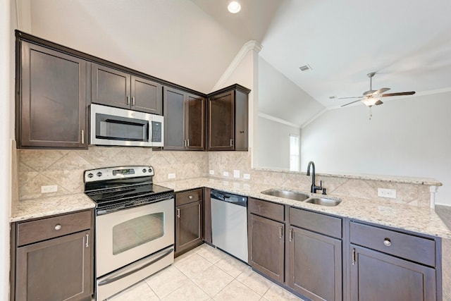 kitchen featuring light stone counters, lofted ceiling, sink, backsplash, and stainless steel appliances