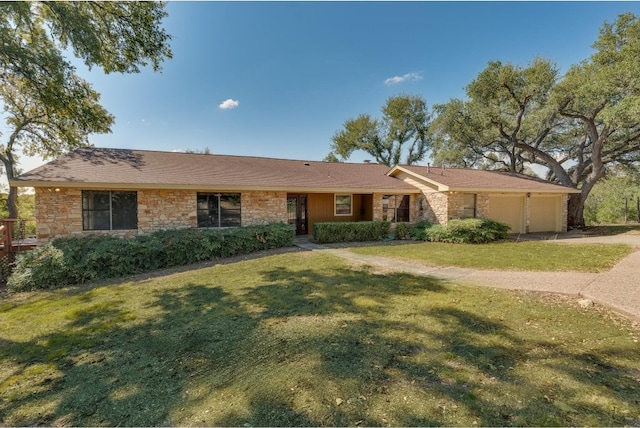 ranch-style house featuring stone siding, an attached garage, driveway, and a front lawn