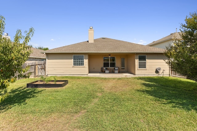 rear view of property with ceiling fan, a patio area, and a yard