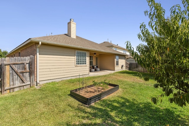 rear view of property with a lawn, ceiling fan, and a patio