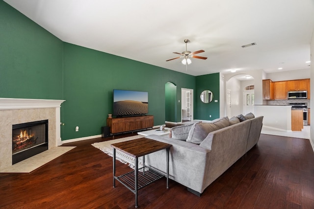 living room featuring dark hardwood / wood-style floors, ceiling fan, and a premium fireplace