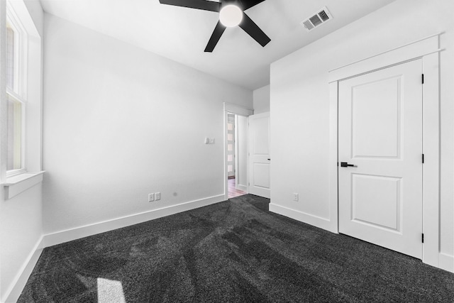 unfurnished bedroom with dark colored carpet and ceiling fan