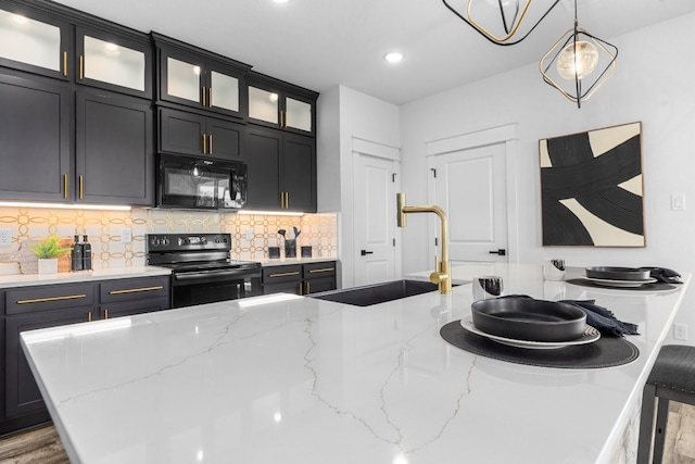 kitchen featuring hanging light fixtures, sink, backsplash, black appliances, and hardwood / wood-style flooring