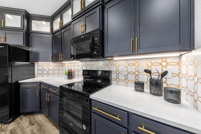 kitchen featuring light stone counters, light hardwood / wood-style flooring, backsplash, and black appliances