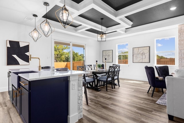 kitchen featuring a kitchen island with sink, hardwood / wood-style flooring, coffered ceiling, plenty of natural light, and decorative light fixtures