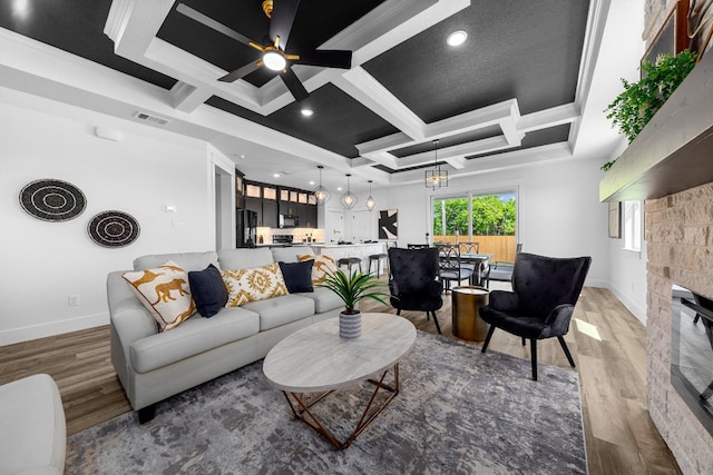 living room featuring ceiling fan, coffered ceiling, ornamental molding, and wood-type flooring