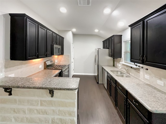 kitchen with light hardwood / wood-style flooring, a kitchen breakfast bar, vaulted ceiling, sink, and stainless steel appliances