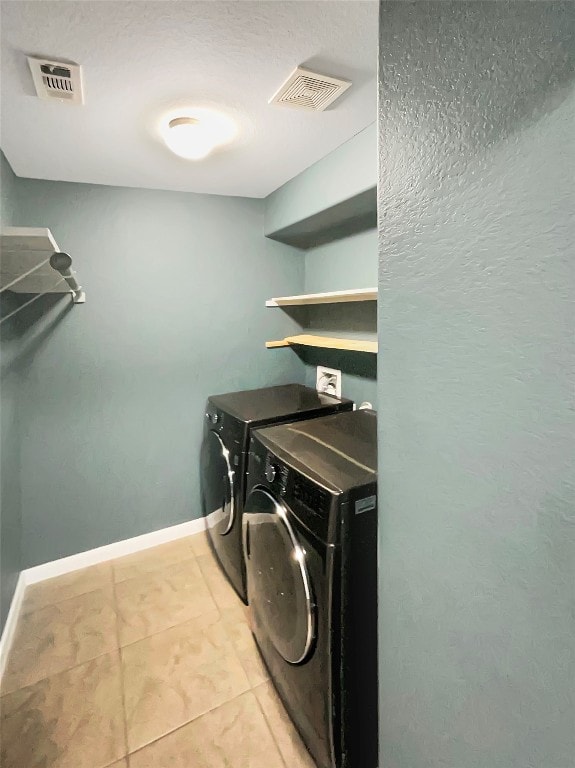 clothes washing area featuring light tile patterned floors and washer and clothes dryer