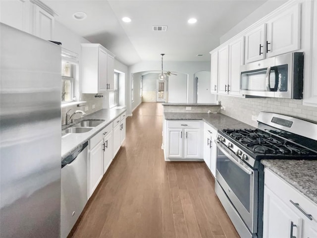 305 Rock Mill Loop, Georgetown, TX 78626 - kitchen featuring stainless steel appliances, a sink, white cabinetry, decorative backsplash, and arched walkways