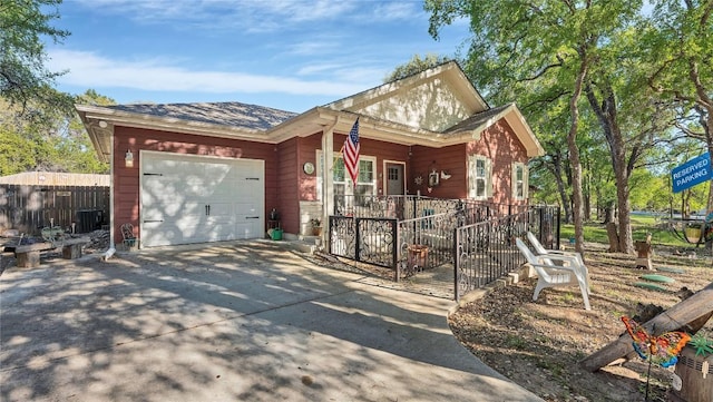 view of front of home featuring fence, driveway, an attached garage, covered porch, and central AC