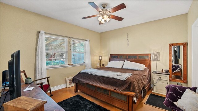 bedroom featuring wood finished floors, a ceiling fan, and baseboards