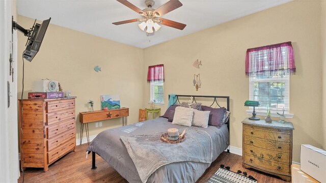 bedroom with ceiling fan, baseboards, and wood finished floors