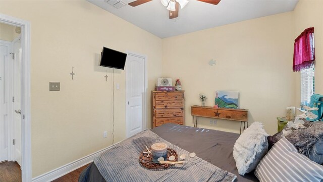 bedroom featuring baseboards, wood finished floors, visible vents, and ceiling fan