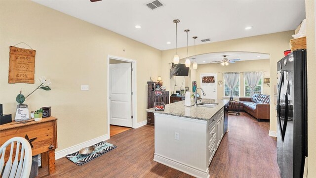 kitchen featuring visible vents, arched walkways, freestanding refrigerator, ceiling fan, and a sink