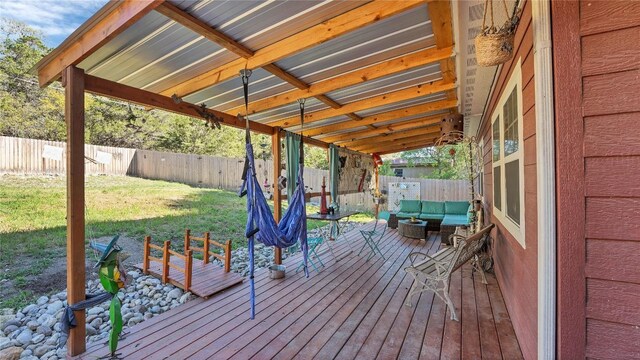 wooden terrace featuring an outdoor living space, a lawn, and a fenced backyard