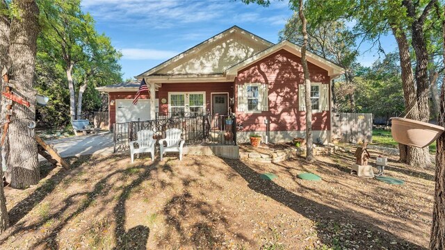 view of front of home with a porch, an attached garage, concrete driveway, and fence