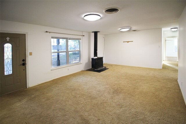 unfurnished living room with carpet floors and a wood stove