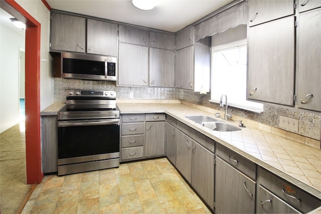 kitchen with sink, backsplash, stainless steel appliances, tile countertops, and light colored carpet