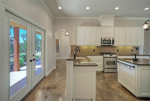 kitchen with dark stone countertops, sink, stainless steel appliances, kitchen peninsula, and white cabinets