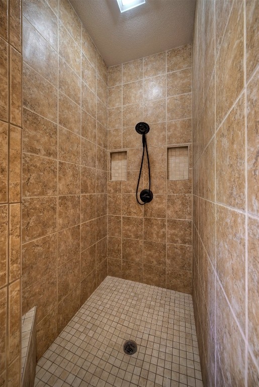 bathroom featuring a textured ceiling and a tile shower