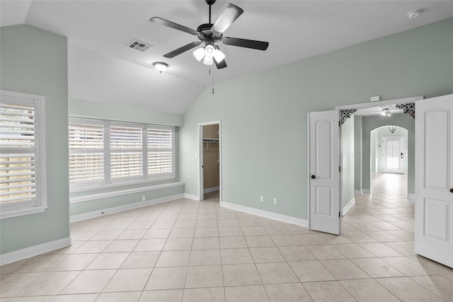 unfurnished bedroom featuring ceiling fan, lofted ceiling, light tile patterned floors, and a spacious closet