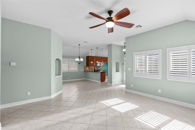 unfurnished living room with ceiling fan with notable chandelier, light tile patterned floors, and a wealth of natural light