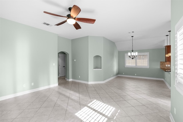 tiled spare room featuring ceiling fan with notable chandelier