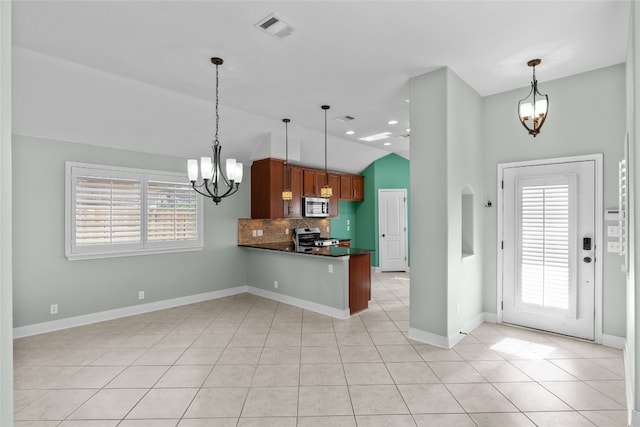 kitchen with lofted ceiling, light tile patterned floors, kitchen peninsula, a chandelier, and stainless steel appliances