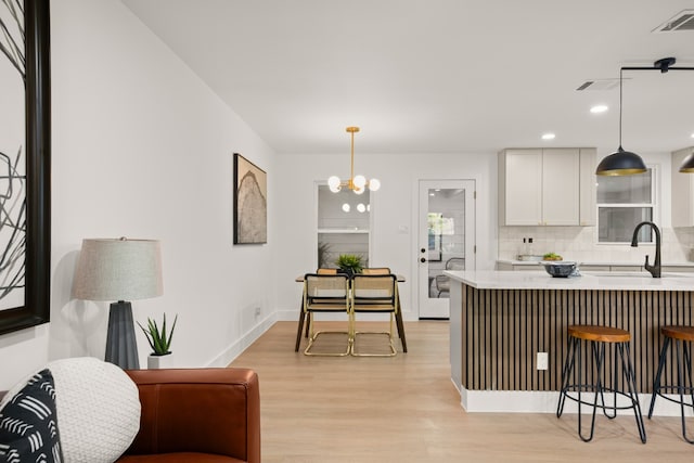 kitchen featuring pendant lighting, light hardwood / wood-style floors, white cabinetry, and sink