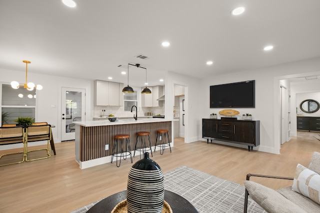 living room featuring a notable chandelier, sink, and light hardwood / wood-style flooring