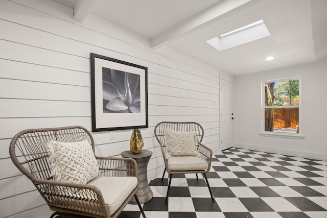 living area featuring a skylight, wooden walls, and beamed ceiling